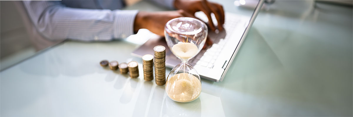 Pièces de monnaie à côté d'un sablier sur une bureau symbolisant le compte épargne-temps en entreprise