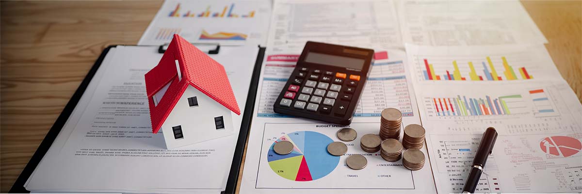 calculatrice à côté d'une maison sur un bureau pour représenter la plus-value de cessions des LMNP qui change en 2025