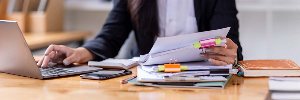 femme d'affaires fouillant dans ses papiers pour vérifier la bonne application de délai de conservation de ses documents fiscaux