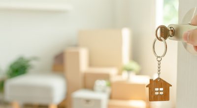 main sur une porte ouverte montrant des cartons dans un appartement d'une personne ayant bénéficié de l'aide 1 % logement