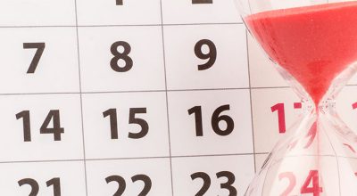 sablier avec sable rouge devant un calendrier qui symbolise les changements en entreprise en juillet 2024