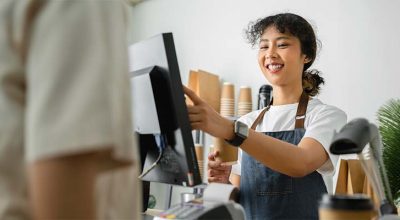 serveuse à la caisse qui doit se conformer à la nouvelle obligation de certification des logiciels de caisse