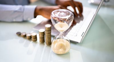Pièces de monnaie à côté d'un sablier sur une bureau symbolisant le compte épargne-temps en entreprise
