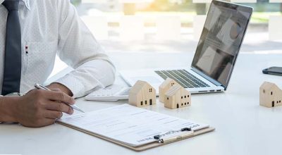 Homme d'affaires en chemise en train de remplir un formulaire dans le cadre de sa déclarations des biens immobiliers