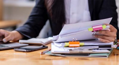 femme d'affaires fouillant dans ses papiers pour vérifier la bonne application de délai de conservation de ses documents fiscaux