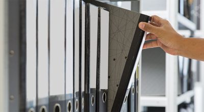 employeur prenant un dossier dans une étagère en se demandant quels sont les délais de conservation des documents en entreprise