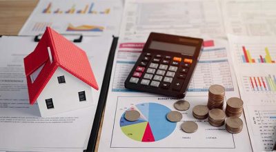plus-value-cession-lmnp calculatrice à côté d'une maison sur un bureau pour représenter la plus-value de cessions des LMNP qui change en 2025