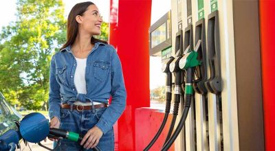 femme salariée qui sourit à la pompe à essence car elle a bénéficié de la Prime carburant en 2026